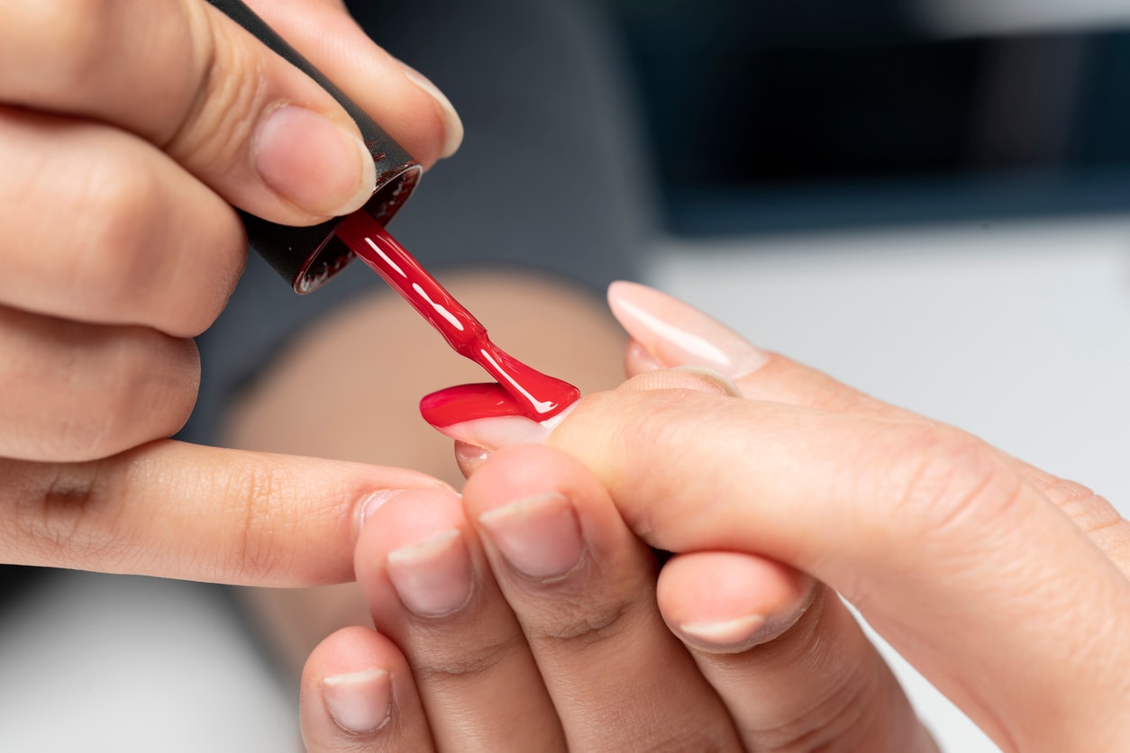 Nail technician applying red polish during a manicure